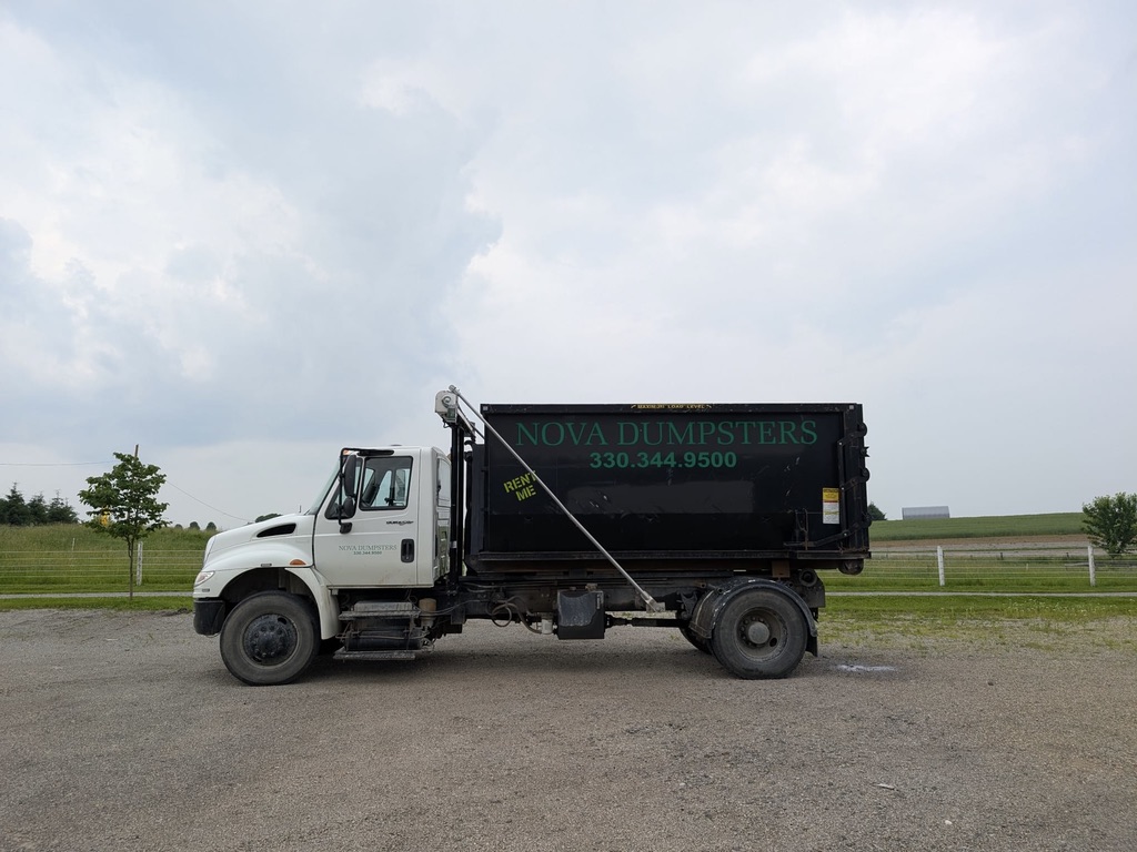 Nova Dumpsters truck with a full bin staged in an open field