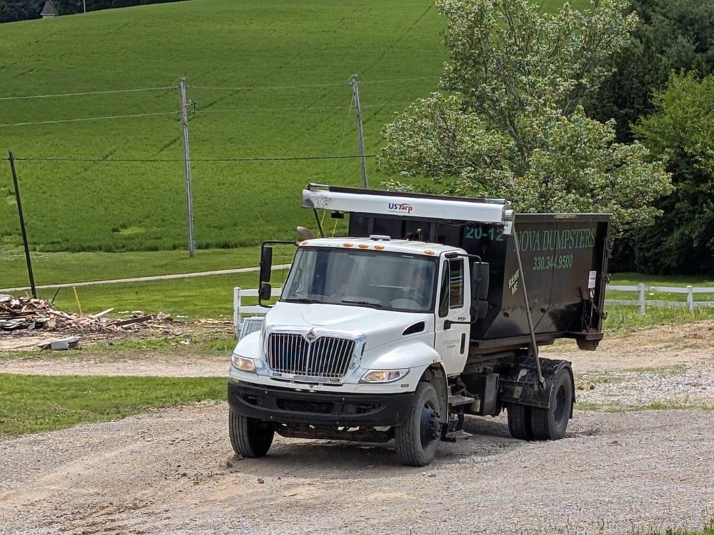 Nova Dumpsters roll-off truck arriving at a rural job site